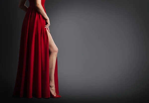 Женская нога и красное платье изолированы на черном фоне, сексуальные ноги — стоковое фото