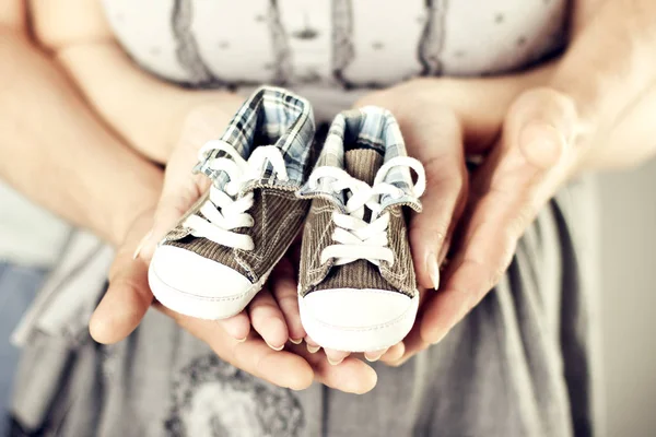 Zapatillas de deporte para bebés recién nacidos en las manos de la familia, los padres par de botines recién nacidos — Foto de Stock