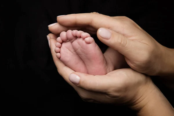 Pies del bebé recién nacido, madre sosteniendo las piernas del niño recién nacido en la mano — Foto de Stock