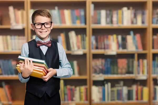 学校図書館で幸せな子供本を持っている、よく服を着た生徒の少年 — ストック写真