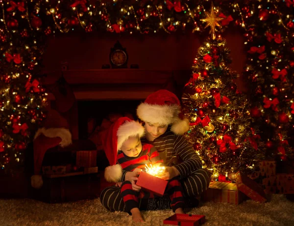 Natal crianças abertura iluminação apresenta presentes sob árvore de Natal — Fotografia de Stock