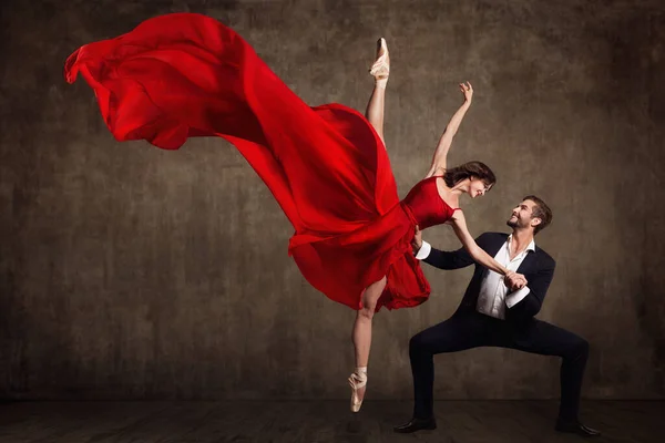 Stock image Ballet Couple Dance, Beautiful Woman in Red Dress and Man in Suit, Ballerina in Fluttering Flying Fabric