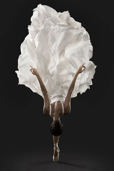 芭蕾舞女演员优雅地跳在白色丝绸衣服 芭蕾舞团舞鞋在飘扬的衣服 黑色背衬 — 图库照片