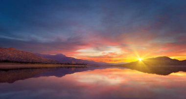 Gün doğumunda tepelerle çevrili göl