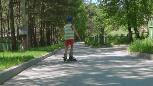 晴れた日の少年ローラーブレード 安全なローラー スケートに乗って子供の身に着けている安全ヘルメット 子供のためのアクティブなアウトドア スポーツ スローモーション — ストック動画