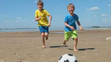 Mutlu kardeşler sahip eğlenceli oynarken futbol güneşli gün ağır çekim Plaj