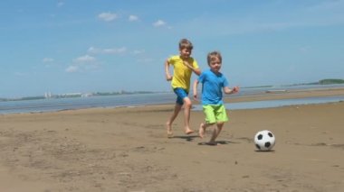 mutlu çocuklar eğlenmek ve kumsalda futbol oynamak. Yaz tatil aktivitesi.