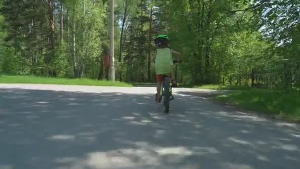 幸せな 歳子少年の私道 緑豊かな公園で 自転車に乗って — ストック動画