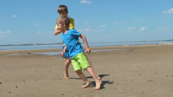 活跃的孩子们在沙滩上踢足球 兄弟在海边踢足球 — 图库视频影像