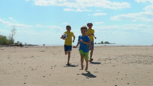 Trzech Dzieci Biegają Piłki Nożnej Piaszczystej Plaży Zwolnionym Tempie — Wideo stockowe