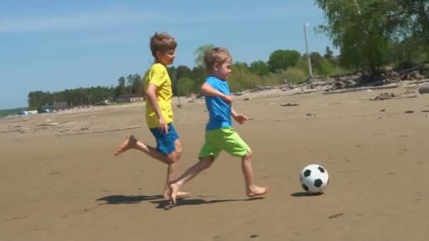 两个男孩在沙滩上踢足球慢动作 兄弟在户外玩足球 — 图库视频影像