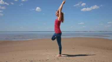 Pratik yoga ağaç poz Kum Plajı güzel genç kadın. 