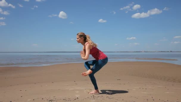 阳光明媚的一天 年轻女子在沙滩上练习瑜伽 — 图库视频影像