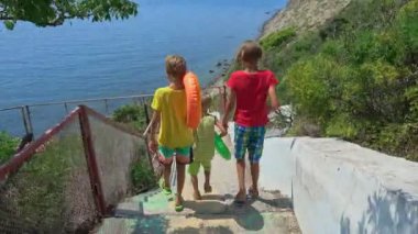 Üç erkek mavi denize aşağı in. Çocuk Resort plajda yüzmek.