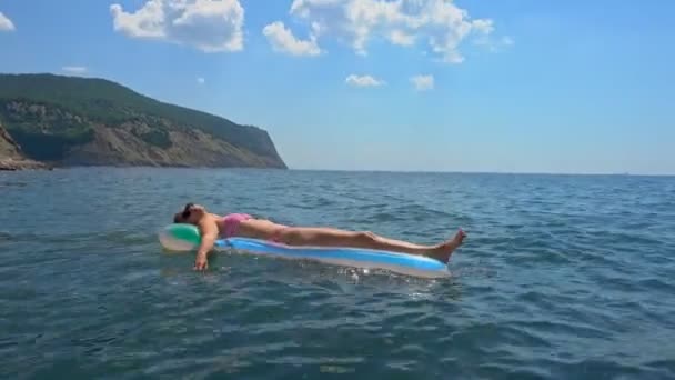 年轻的妇女晒黑的充气床垫在蓝色天空下的蓝绿色蓝色水在夏季假期 — 图库视频影像