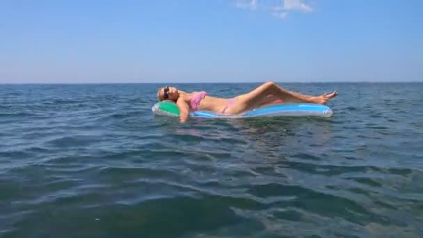 海でマットレスの上の夏の休暇を楽しんでいると カメラを見て幸せな女の子 — ストック動画