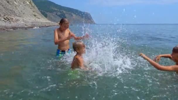 海の水でお互いの子ども遊びとスプラッシュ 夏の休暇 — ストック動画