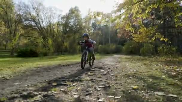 美しい秋の日に小さな子供乗馬の自転車 バイクのヘルメットを身に着けている活発な少年 安全性 スポーツ レジャーは子供の概念 — ストック動画