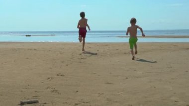 Sahilde denize çalışan mutlu çocuklar. Yaz tatil çocuklar birlikte oyun.