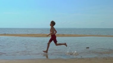 Sahilde sığ suda çalışan mutlu çocuk