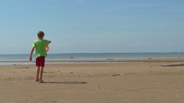 在阳光明媚的日子里 男孩在沙滩上慢动作地扔飞盘 夏季活动 — 图库视频影像
