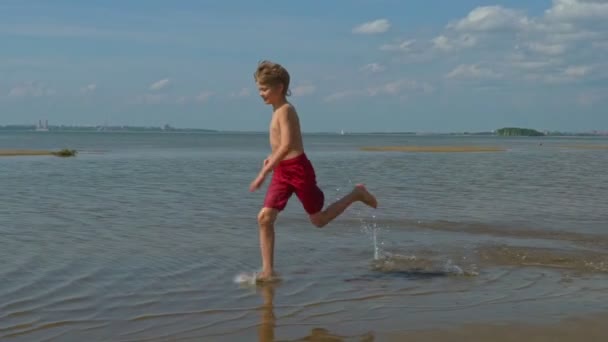 ビーチで走っている幸せな少年 夏休みは海で — ストック動画