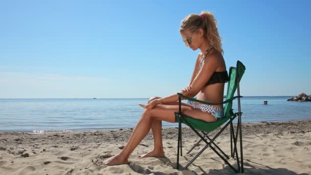 Mujer Joven Que Aplica Protector Solar Cuerpo Sentado Silla Playa — Vídeos de Stock