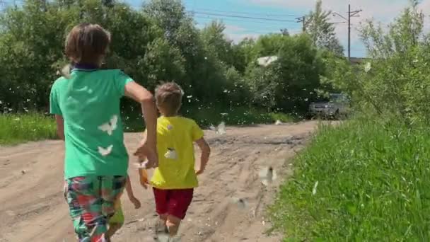 国の道路に沿って実行している子供たち 多くの蝶のそれらのまわりで飛ぶスローモーション — ストック動画