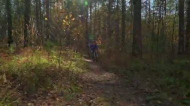 Çocuklar sonbahar güneşli bir günde ormandaki bisiklet sürme. Çocuklar açık havada kask içinde Bisiklete binme