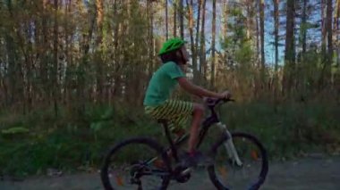 Genç çocuk sonbahar ormanında bir bisikletle. Çocuk açık havada kask içinde Bisiklete binme