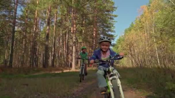 幸せな笑みを浮かべて少年フォレストにヘルメットで自転車に乗る カジュアルウェア 一緒にバイクでサイクリング楽しんで互いに競って彼らの友人 — ストック動画