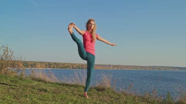 Mladá žena, která dělá bilance jóga na břehu moře v podzimní den. 