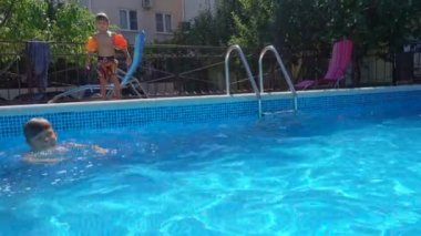 İki erkek havuzda, suda güneşli yaz günde Resort'ta atlama mutlu küçük çocuk