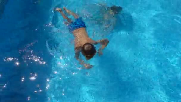 男孩在游泳池里游泳 快乐的小孩在阳光明媚的暑假里跳水 — 图库视频影像