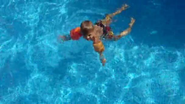 在阳光明媚的日子里 孩子在户外游泳 小男孩一边在游泳池里洗澡 一边学习游泳 — 图库视频影像