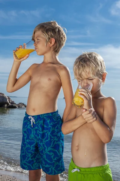 Due Ragazzi Che Bevono Succo Arancia Sulla Spiaggia Sfondo Cielo — Foto Stock