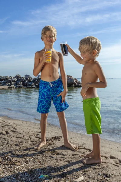 带果汁杯的孩子在沙滩上玩得开心 — 图库照片