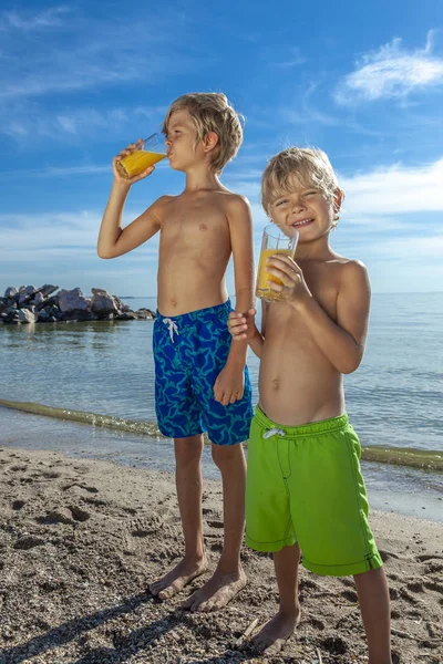快乐微笑的孩子站在沙滩上 在暑假喝新鲜果汁 — 图库照片