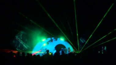 Müzik konserinin ön sahnesi, ön ışıklar ve lazer projeksiyonu. Yaz festivali kalabalığı. Işık gösterisi. Kalabalık tezahürat ve dans.