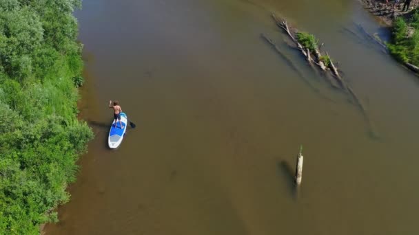 川で泳ぐサップサーフィンのティーンエイジャーの少年 ドローンからの航空写真 — ストック動画