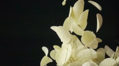 Siyah arka plana düşen patates cipsi yavaş çekim yığını.