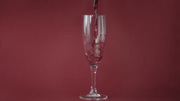 以慢动作将红酒倒入玻璃中 在粉红色背景下 — 图库视频影像