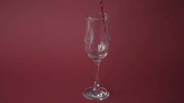 Χύνοντας Κόκκινο Κρασί Στο Γυαλί Από Ροζ Φόντο Αργή Κίνηση — Αρχείο Βίντεο