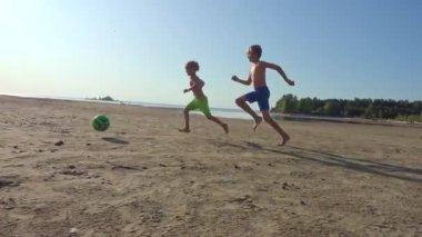 çocuklar runnung ve plajda futbol topu tekme, çocuklar futbol yavaş hareket oynarken