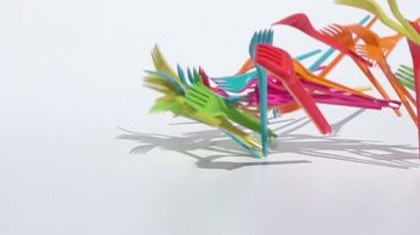 Beyaz arka plan üzerinde yavaş çekimde düşen çok renkli plastik çatallar