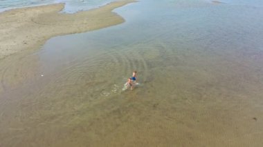 Yaz tatilinde sahilde koşan iki çocuğun hava görüntüsü.