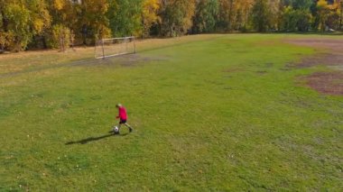 güneşli sonbahar gününde futbol sahasında futbol topu ile çocuk eğitim, havadan görünümü