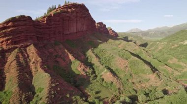 Red Clay Canyon Landscape. A breathtaking panoramic view of a dramatic  landscape, showcasing the vibrant hues of the eroded rock formations, lush green vegetation. Mountain canyon landscape. Drone view