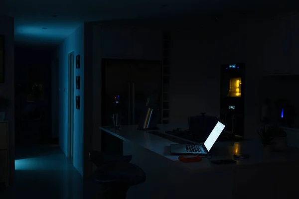 Shot of a laptop illuminated in a kitchen at night