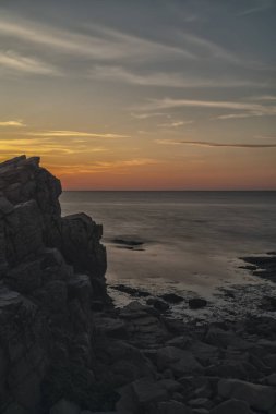 Kayalık plaj manzara alacakaranlıkta. Hovs Hallar, İsveç.